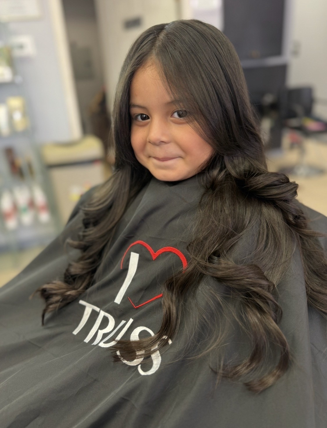 Real client photo from KARY HAIR SALON featuring bouncy voluminous blowout with soft curls and glossy shine, styled in salon chair with mirror reflection