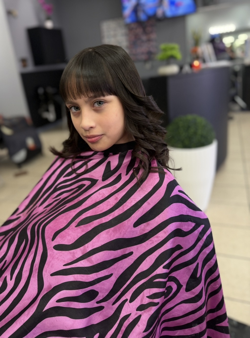 Genuine client photo from KARY HAIR SALON of quinceañera updo with braided crown, romantic curls and hair accessories, back view showing detailed styling work