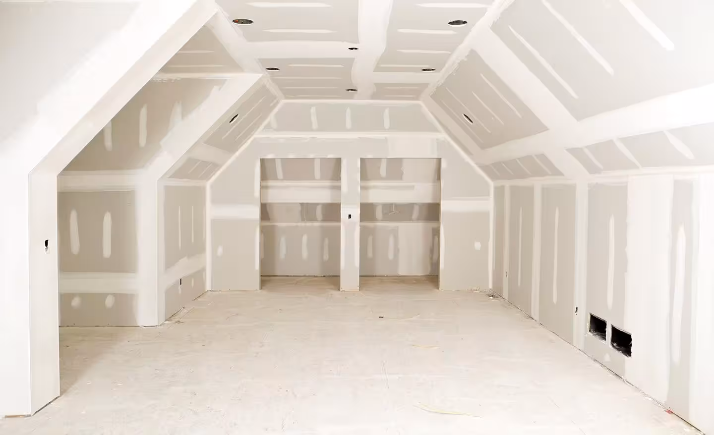Contractor installing and finishing drywall panels in a residential interior room