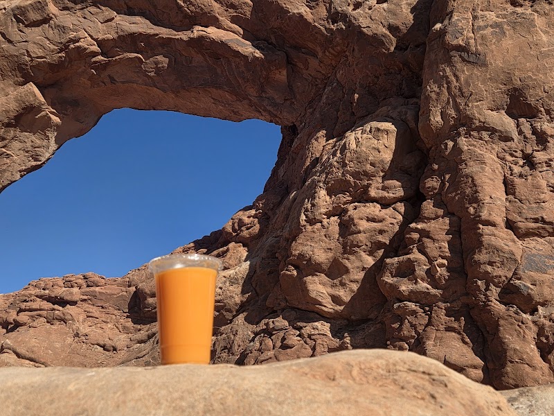 Happy customer enjoying a vibrant superfood smoothie outside the Moab cafe