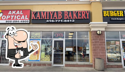 Warm welcoming interior of Kamiyab Bakery in Markham showing wooden display cases filled with fresh baked goods, traditional decor and inviting lighting
