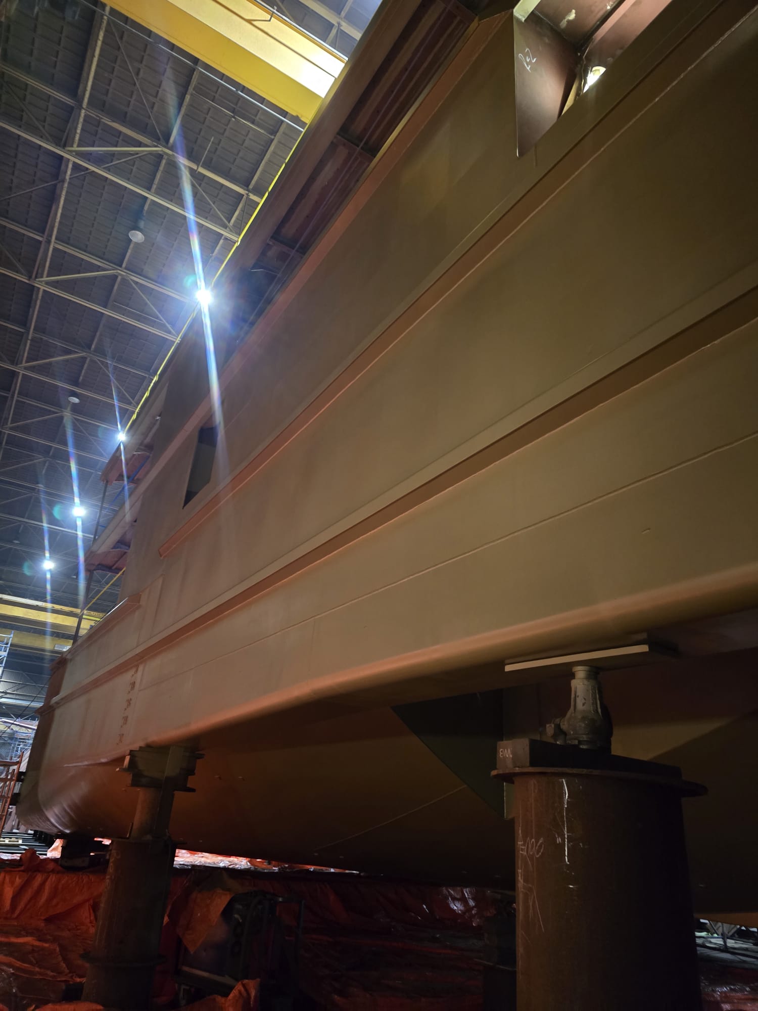 Industrieel schilder in beschermende kleding brengt coating aan in spuitcabine