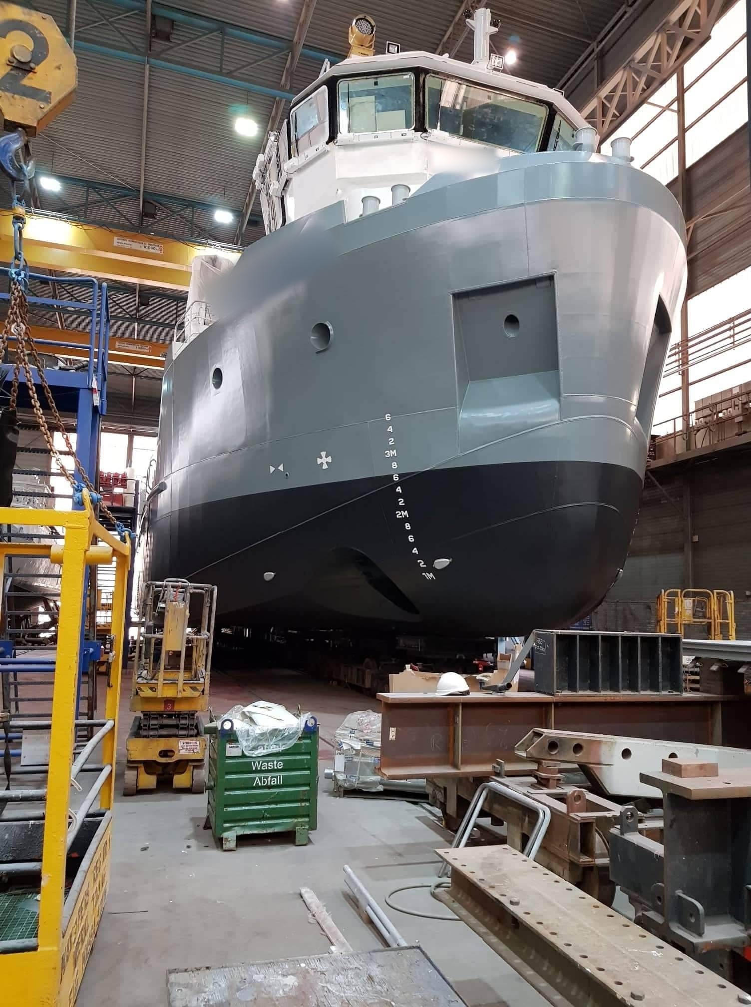 Professionele schilder in beschermende kleding brengt industriële coating en conservering aan op een grote scheepsromp