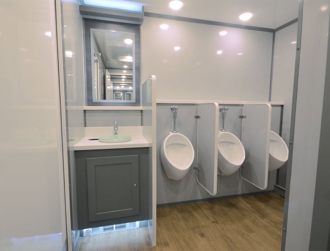Interior of a luxury portable restroom trailer featuring marble countertops, warm ambient lighting, and elegant fixtures