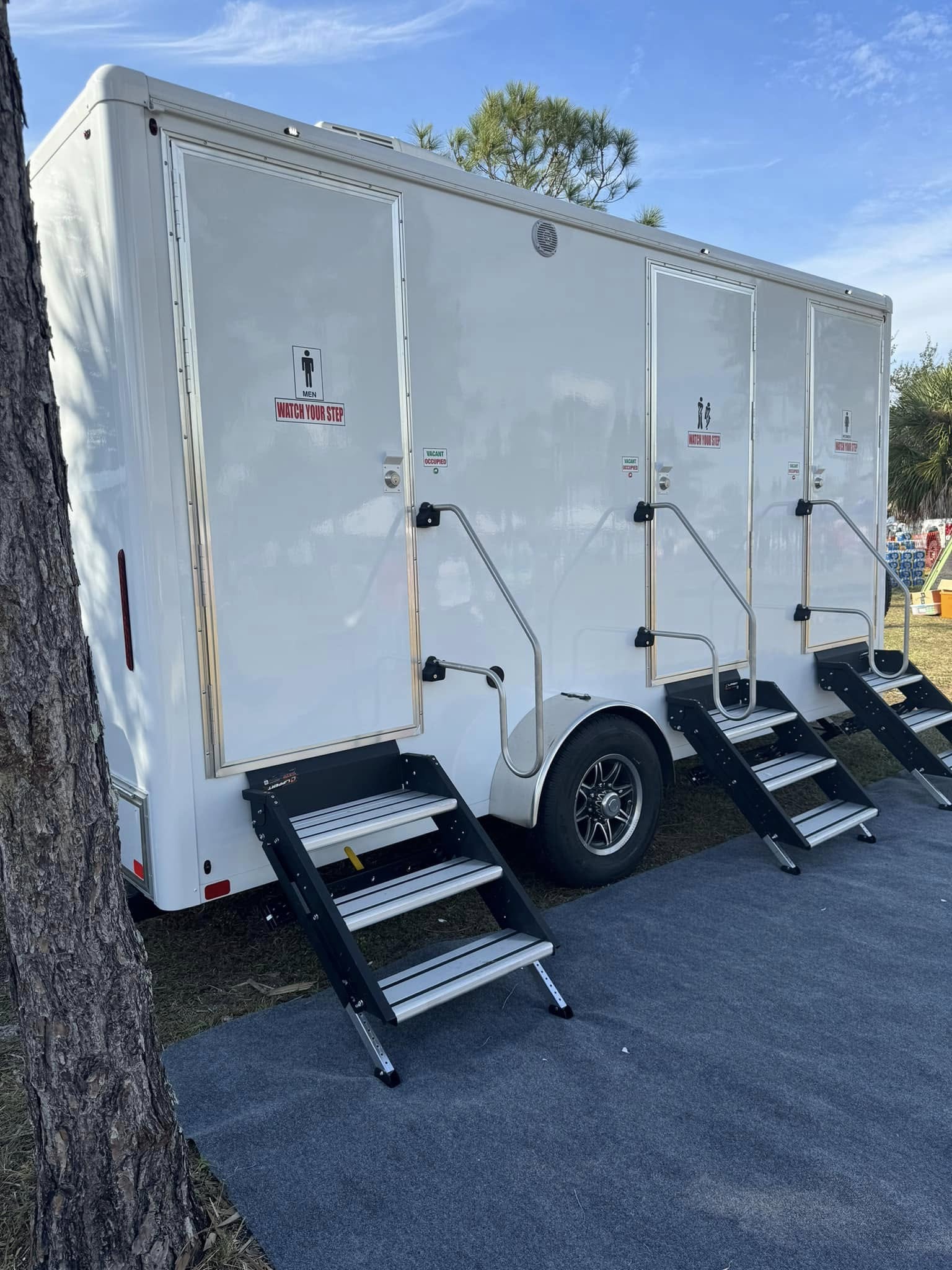 Exterior of a luxury restroom trailer at an evening wedding reception, illuminated by warm string lights