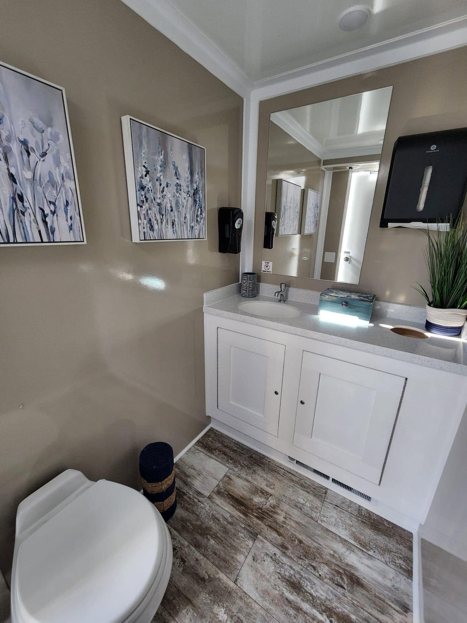 Interior detail of luxury mobile restroom featuring elegant framed mirror, marble vanity, and warm ambient lighting fixtures