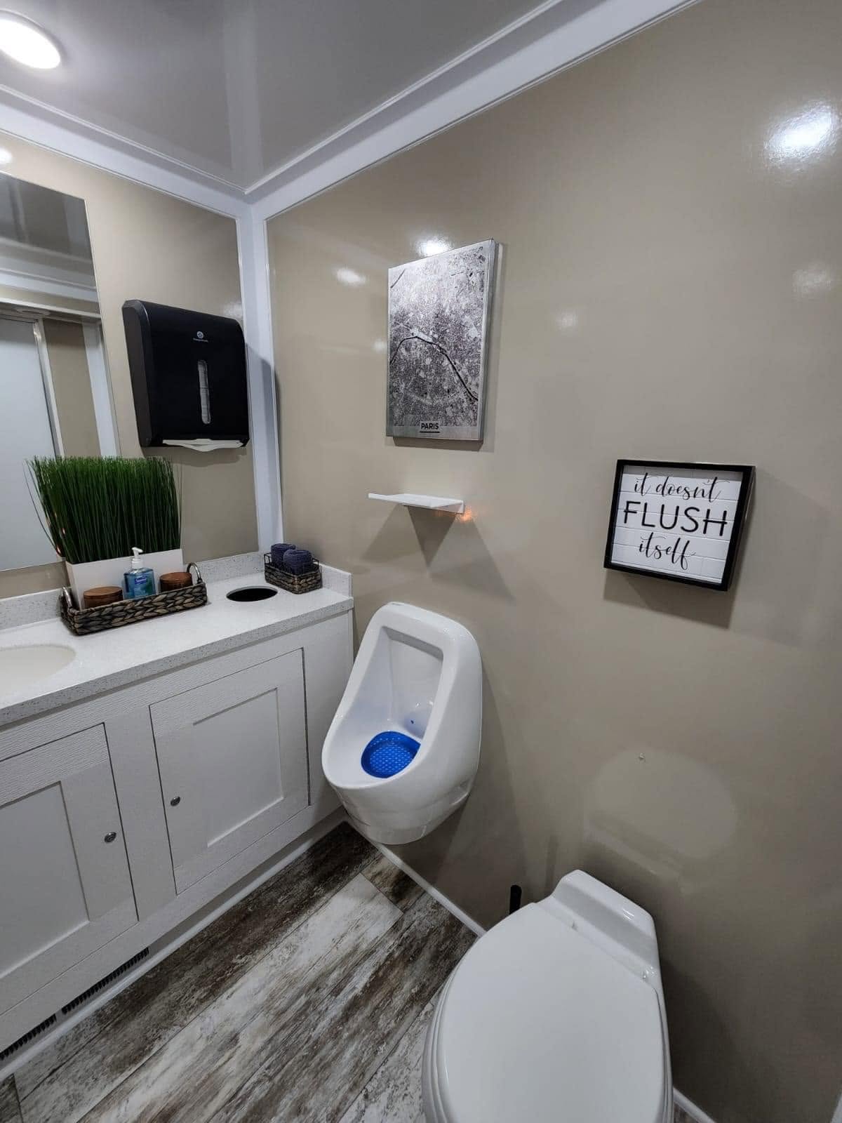 Exterior of pristine white luxury restroom trailer positioned at an upscale outdoor daytime corporate event with tented pavilion
