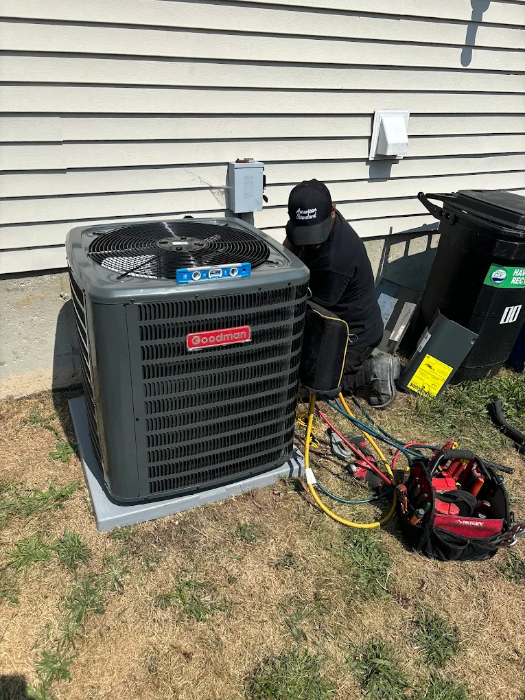 HVAC technician repairing an outdoor central air conditioning condenser unit beside a residential home