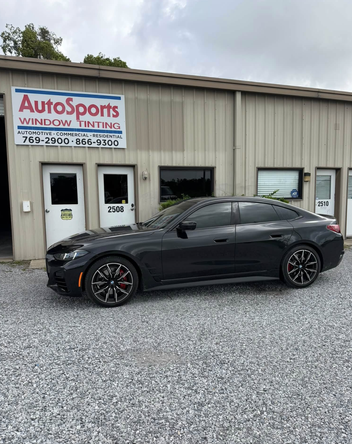 Luxury black sedan with professional ceramic window tint installation reflecting studio lighting