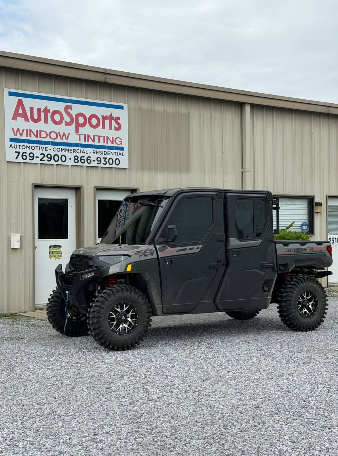 Red sports coupe with dark carbon window tint parked in professional automotive shop