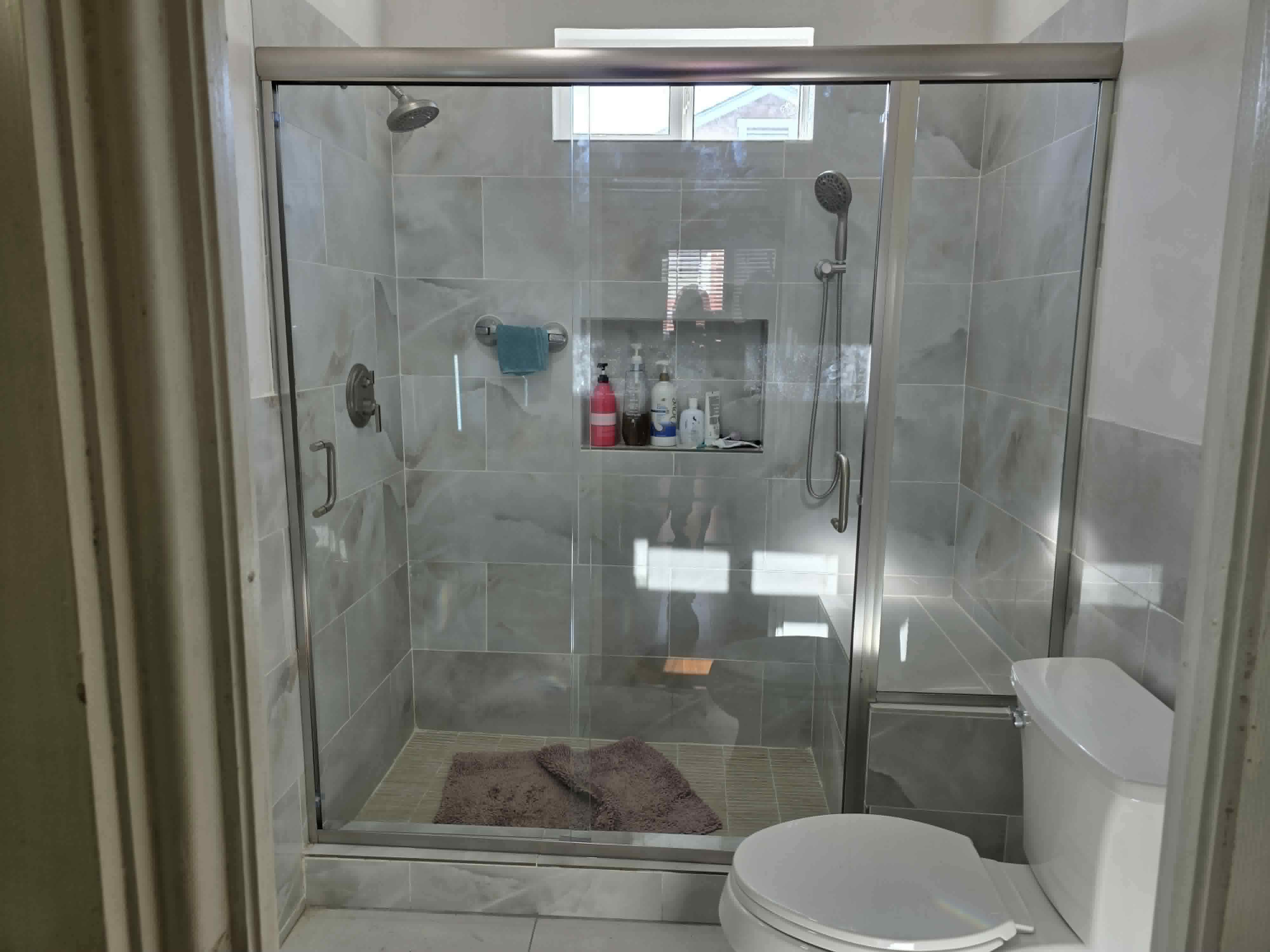 A custom-installed frameless glass shower enclosure in a luxury bathroom.