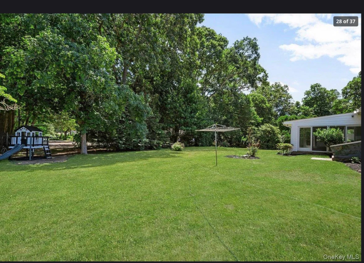 Lush private backyard at 870 Crittens Lane, Southold — a peaceful outdoor retreat with mature trees, open lawn, and room to entertain on a half-acre North Fork property