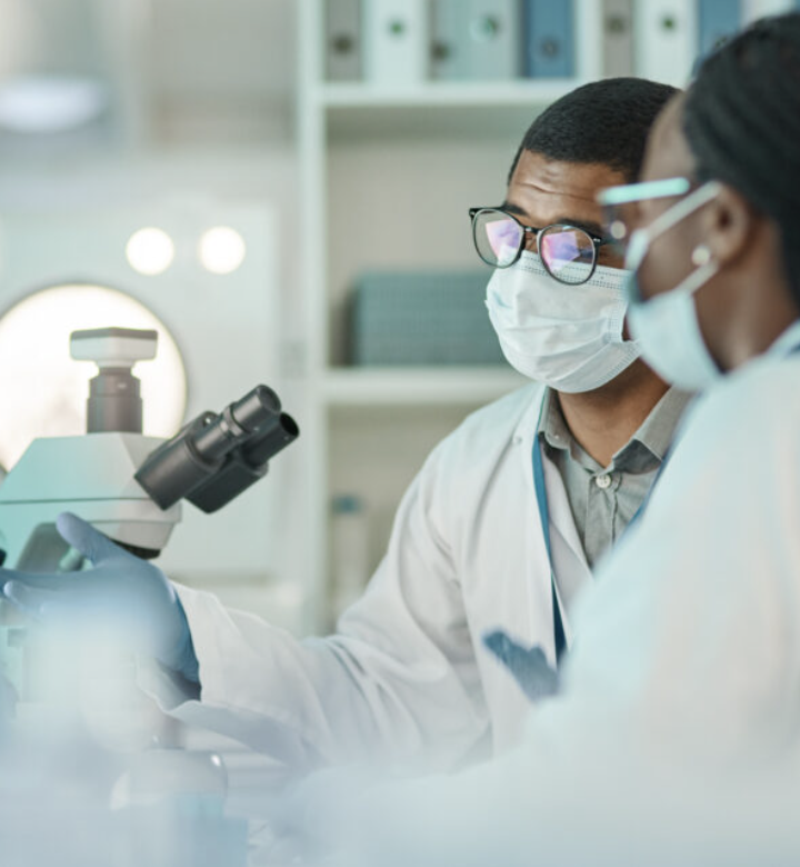 Scientist carefully adjusting a high-powered microscope in a bright, modern research laboratory