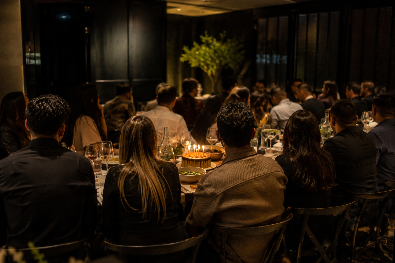 A large, happy family celebrating a birthday at a long banquet table in a modern, bustling Asian buffet restaurant