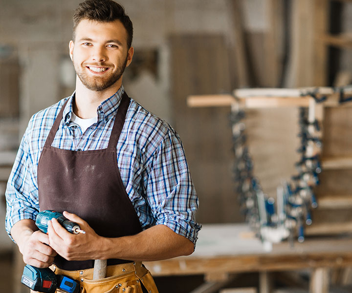 Schreiner bei der präzisen Arbeit an einem Holzmöbel in seiner Werkstatt