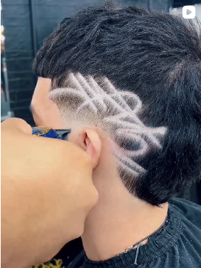 A barber using a straight razor to create a sharp, clean line on a client's beard