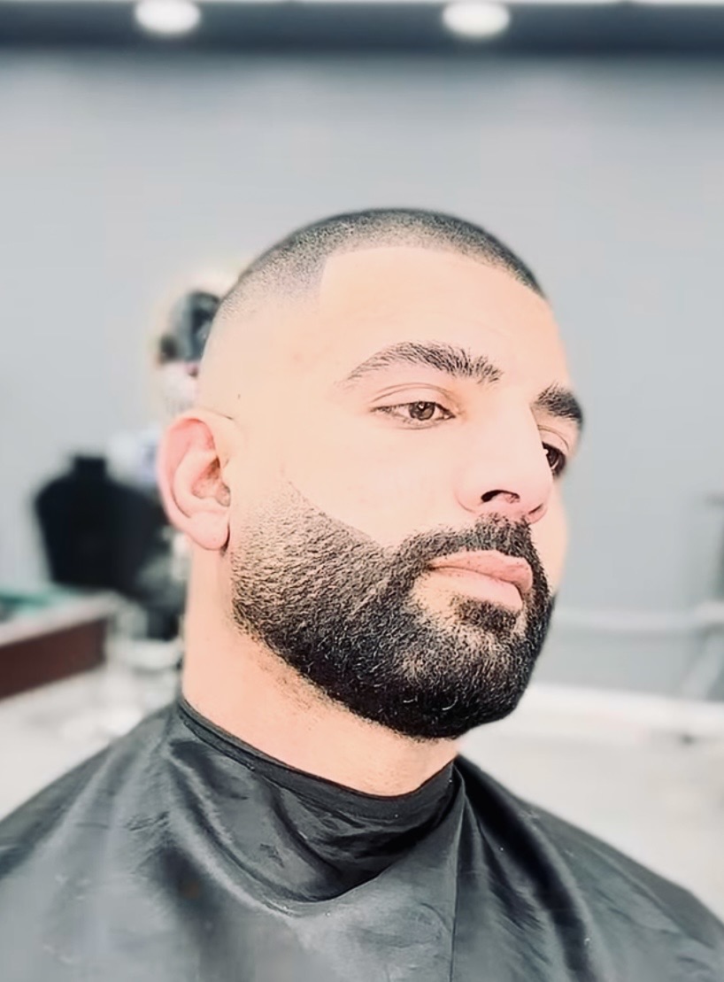 A barber carefully trimming a beard