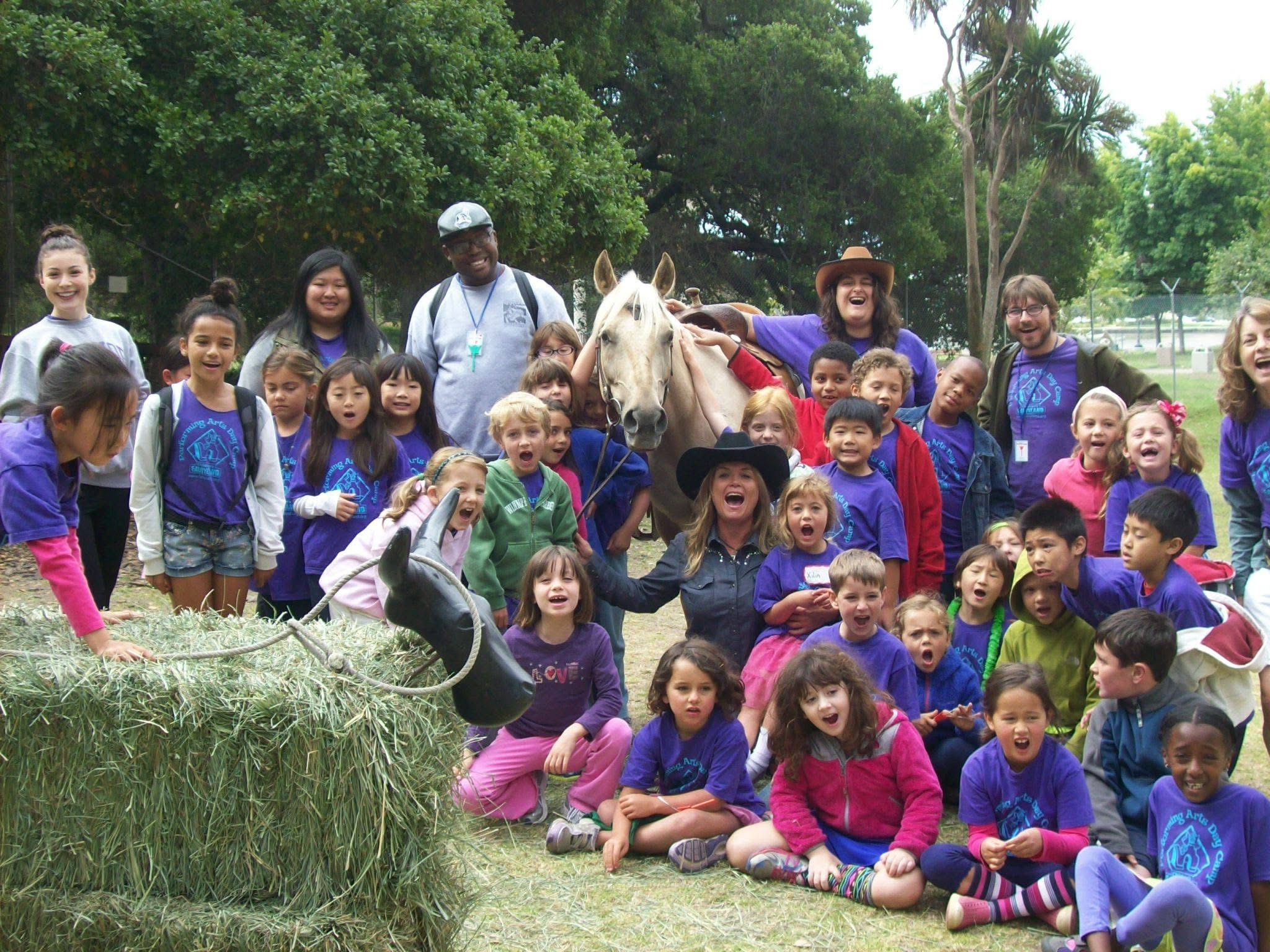 A gentle miniature pony with a braided mane being petted by children