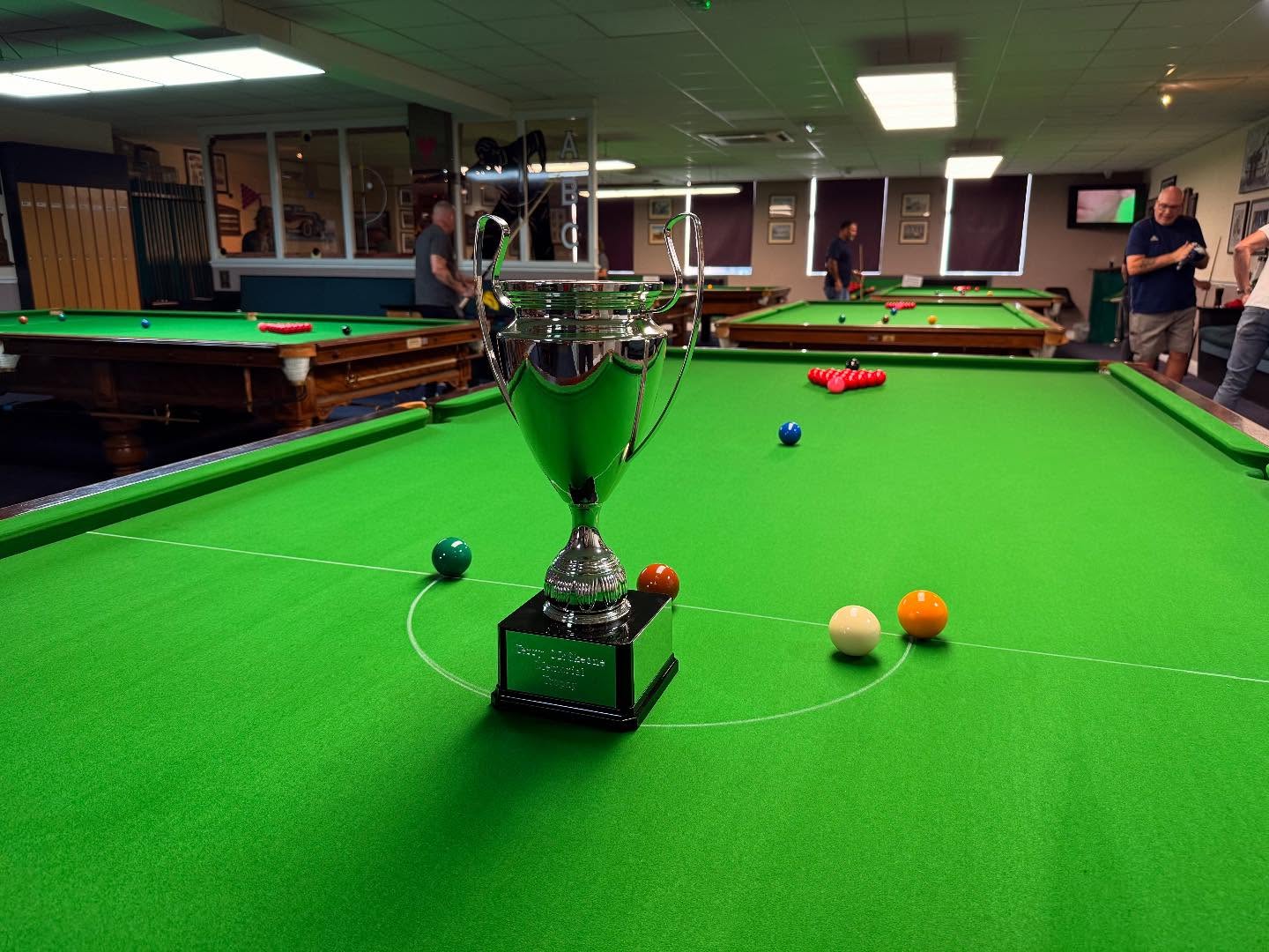 Wide-angle view of ABC Snooker Club's warm and inviting interior with burgundy accents and elegant lounge seating around tournament-spec tables