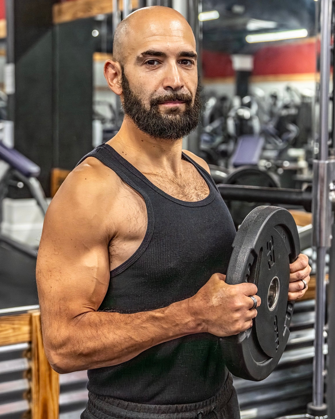 Professional male fitness coach and trainer with chiseled physique standing in industrial gym preparing FIZEEK FREEK challenge competitors