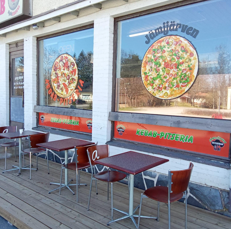 Puu-uunissa paistettu rustiikkinen pizza tarjoillaan puisella lautasella Jämijärven pitseriassa lämpimässä paikallisessa tunnelmassa