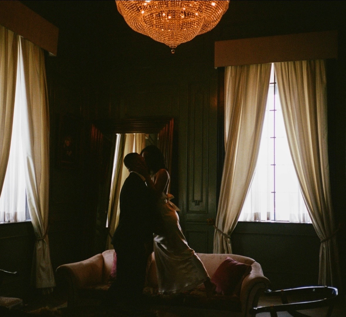 Kahlil and Kayla sharing a romantic moment during their engagement photoshoot, featuring moody lighting and elegant burgundy aesthetics