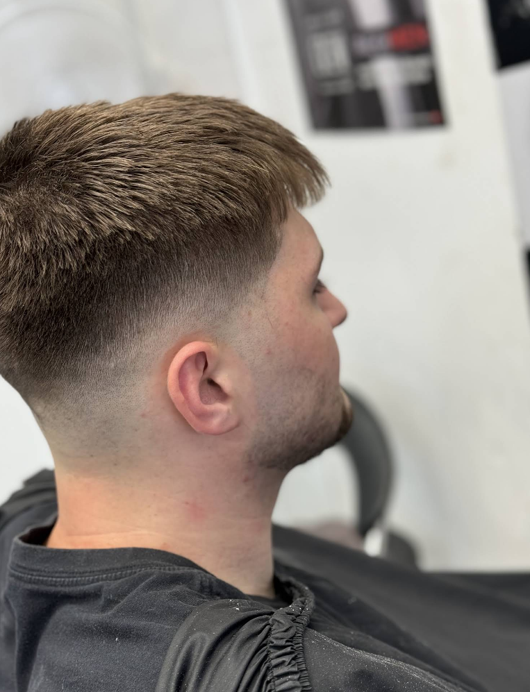 Turkish master barber performing precision skin fade haircut on client in luxurious dark barbershop with gold accents
