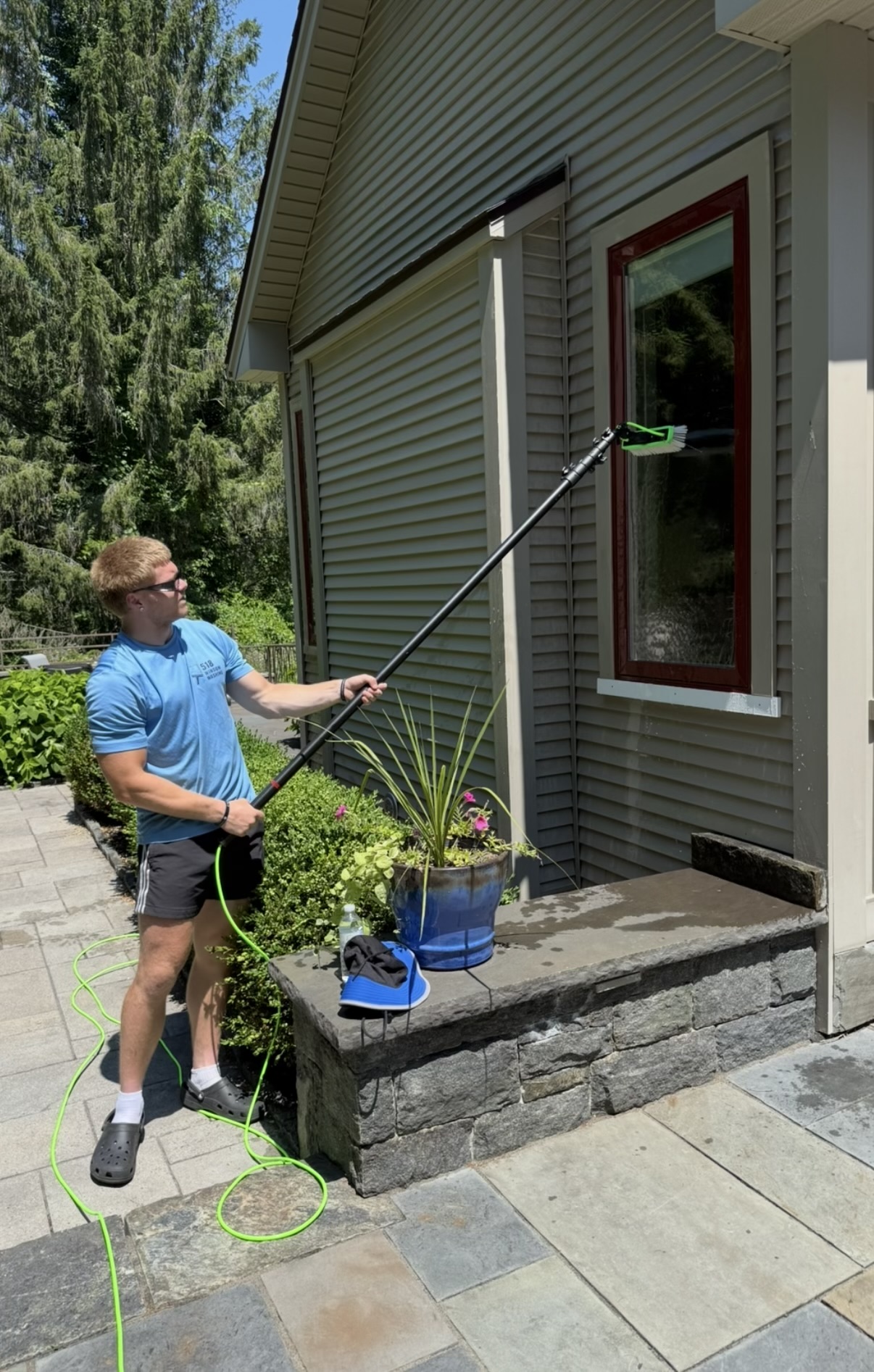 Friendly 518 Window Washing technician in a clean uniform smiling at a residential property in Albany