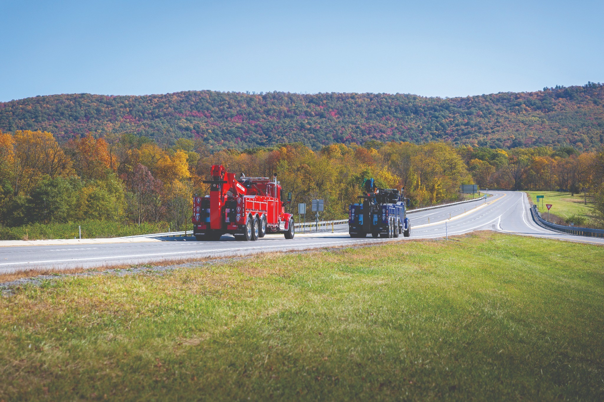 Heavy-duty wrecker tow truck recovering a large commercial semi-truck on the highway