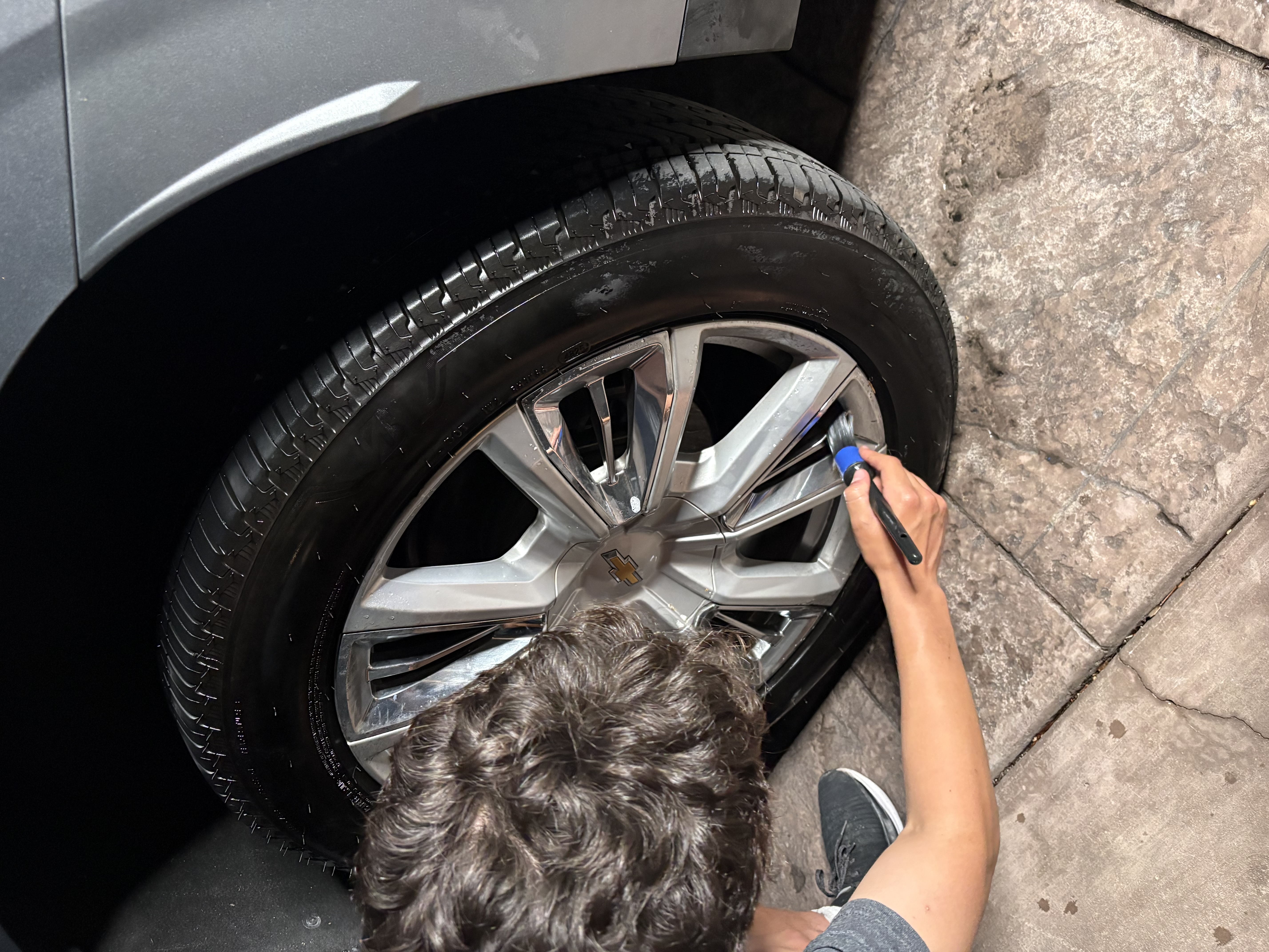Professional detailer hand washing and polishing the exterior of a luxury vehicle