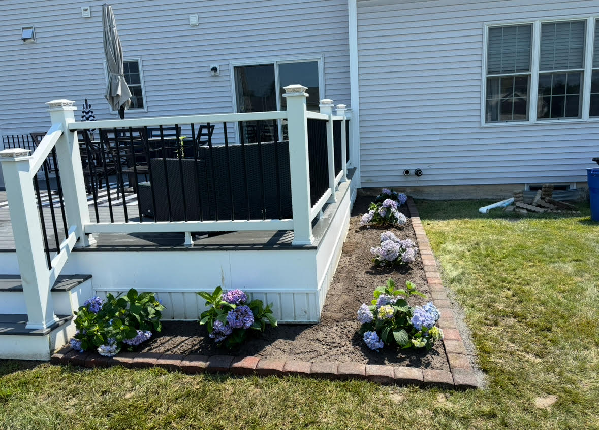 Lush modern backyard with a stone patio and vibrant flower beds under evening light