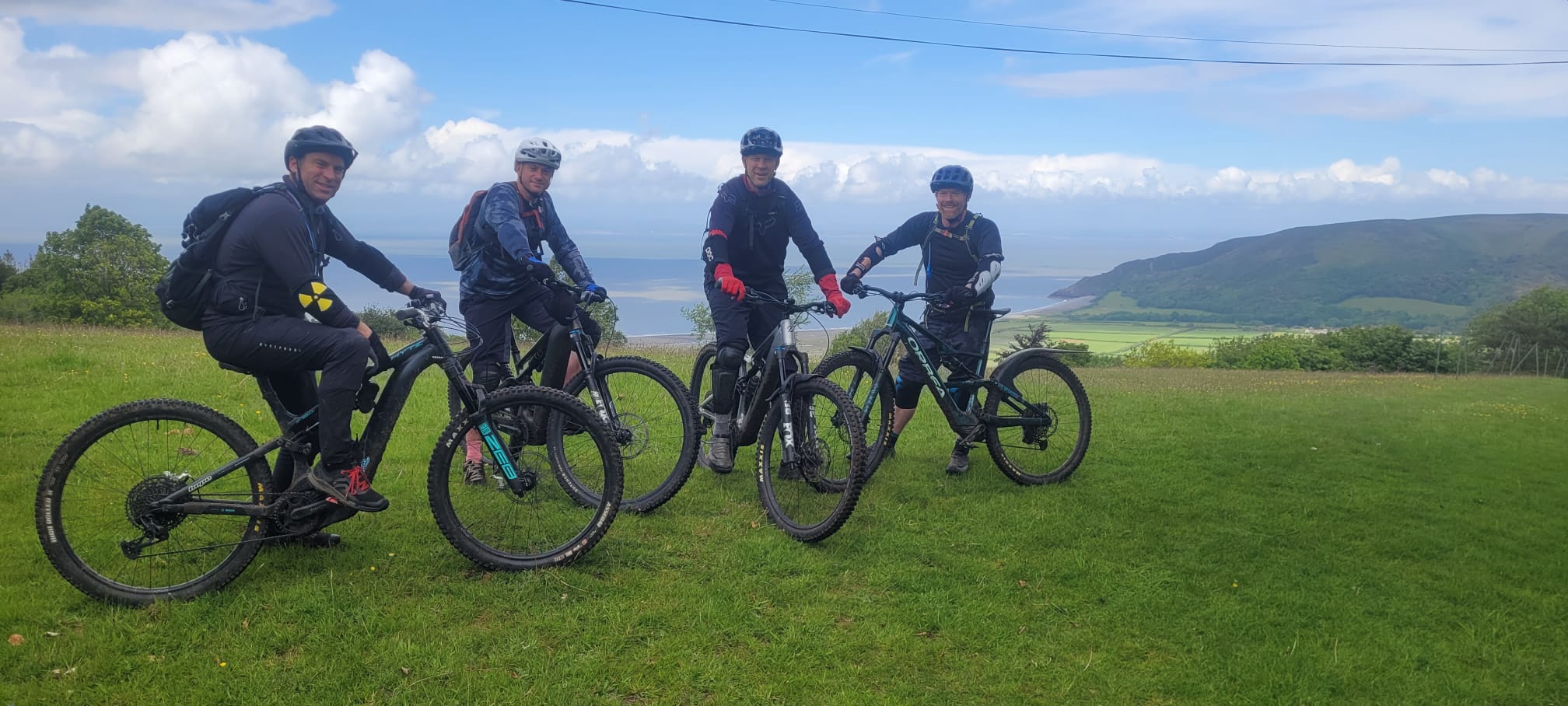 A high-end mountain bike resting against a fence post overlooking the rugged Exmoor coastline