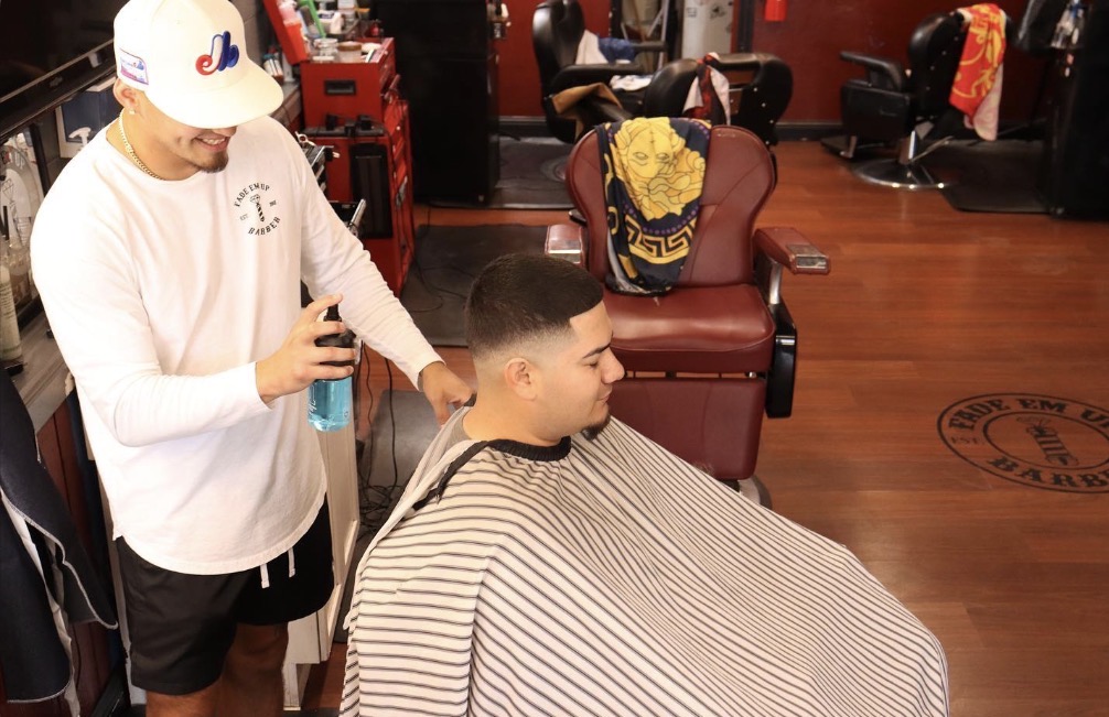 Wide shot of a stylish, modern barbershop interior with vintage leather chairs and moody, atmospheric lighting